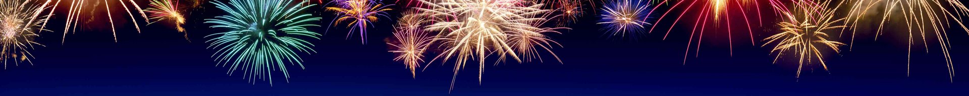 Farverige fyrværkerier eksploderer mod en mørkeblå baggrund. De lysegnistrende lys stråler i forskellige former og farver, hvilket skaber en festlig stemning, der ofte er forbundet med fejringer og specielle lejligheder.